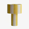 Yellow and white striped woven shade table lamp on a white background