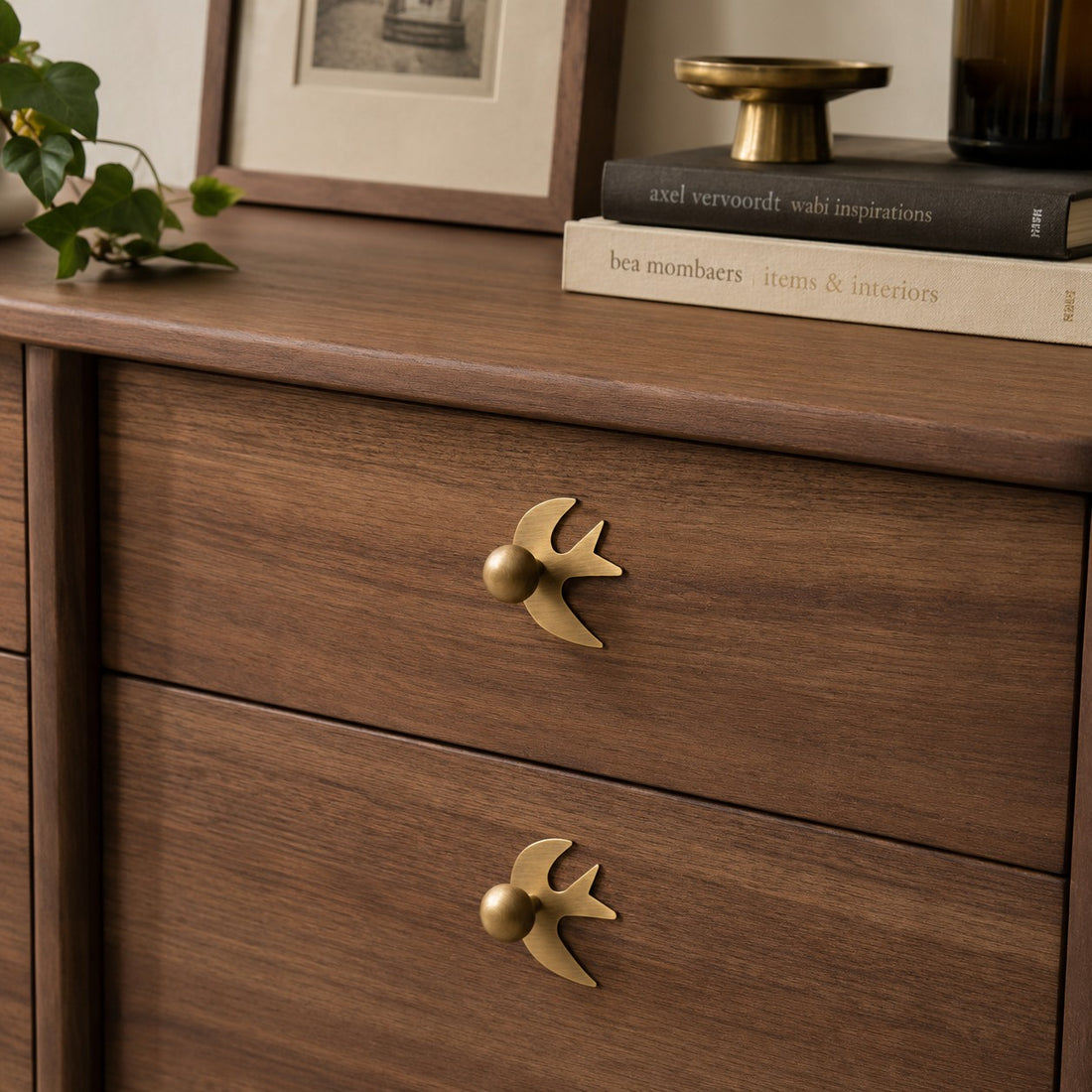 Swallow-shaped brass handles on wood drawers