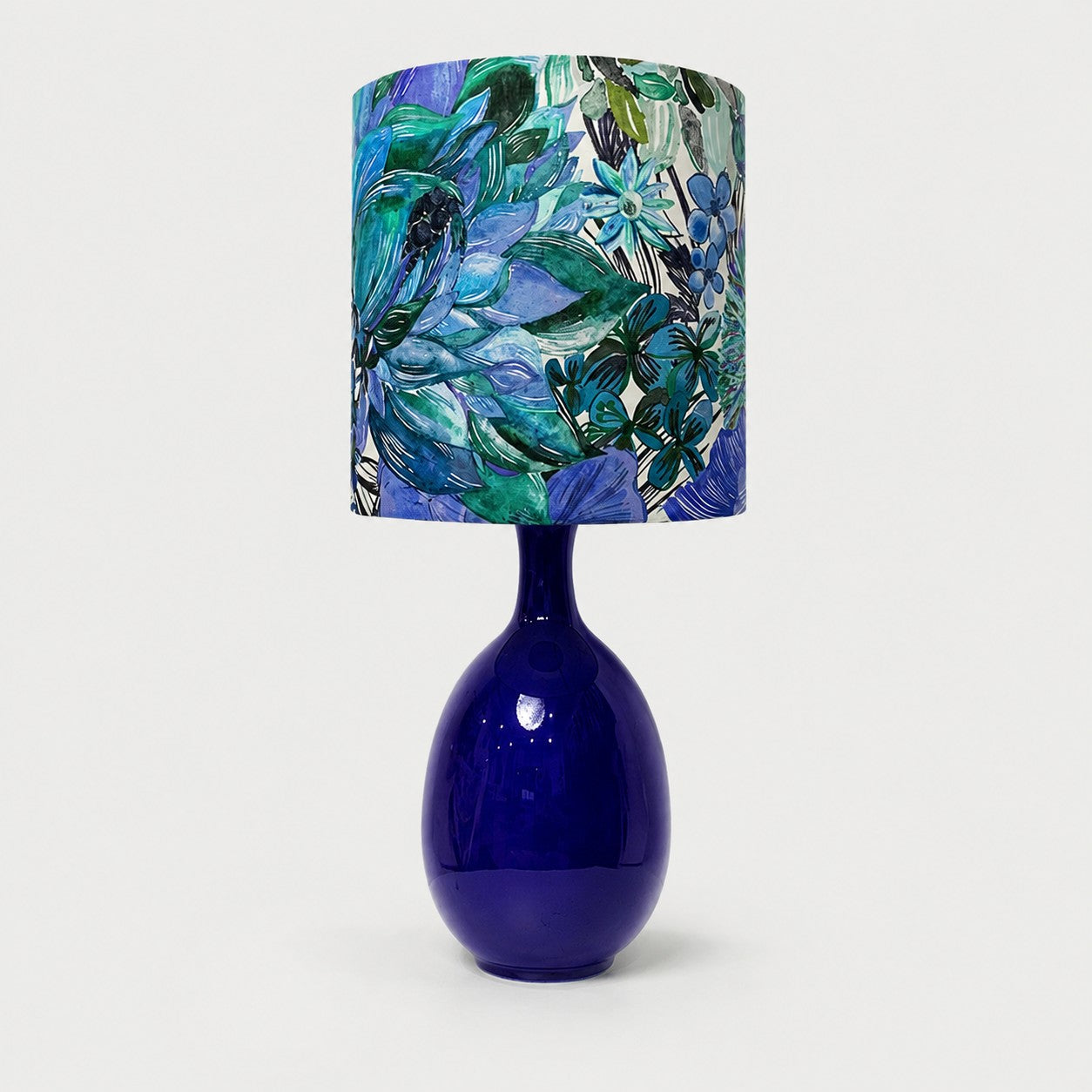 Green botanical fabric ceramic table lamp on plain background