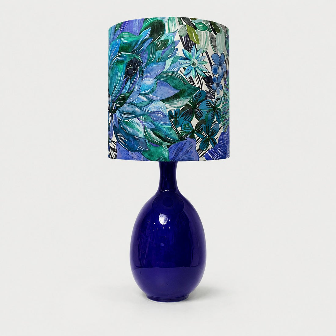 Green botanical fabric ceramic table lamp on plain background