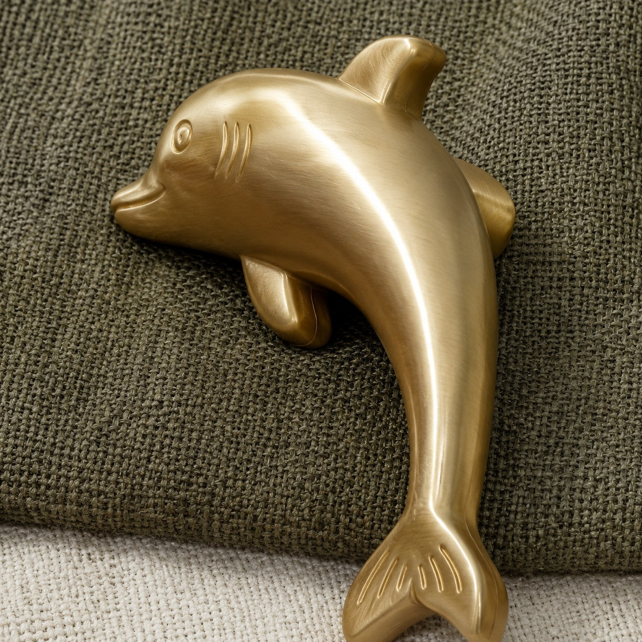 Close-up of the Totem dolphin cabinet handle in natural brass