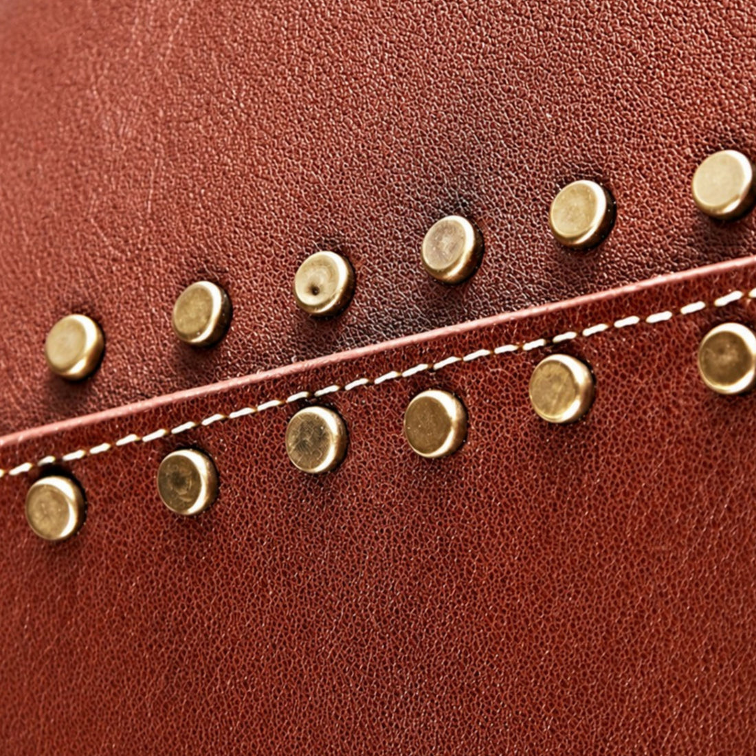 Cognac leather grain, stitching, and antique brass rivets