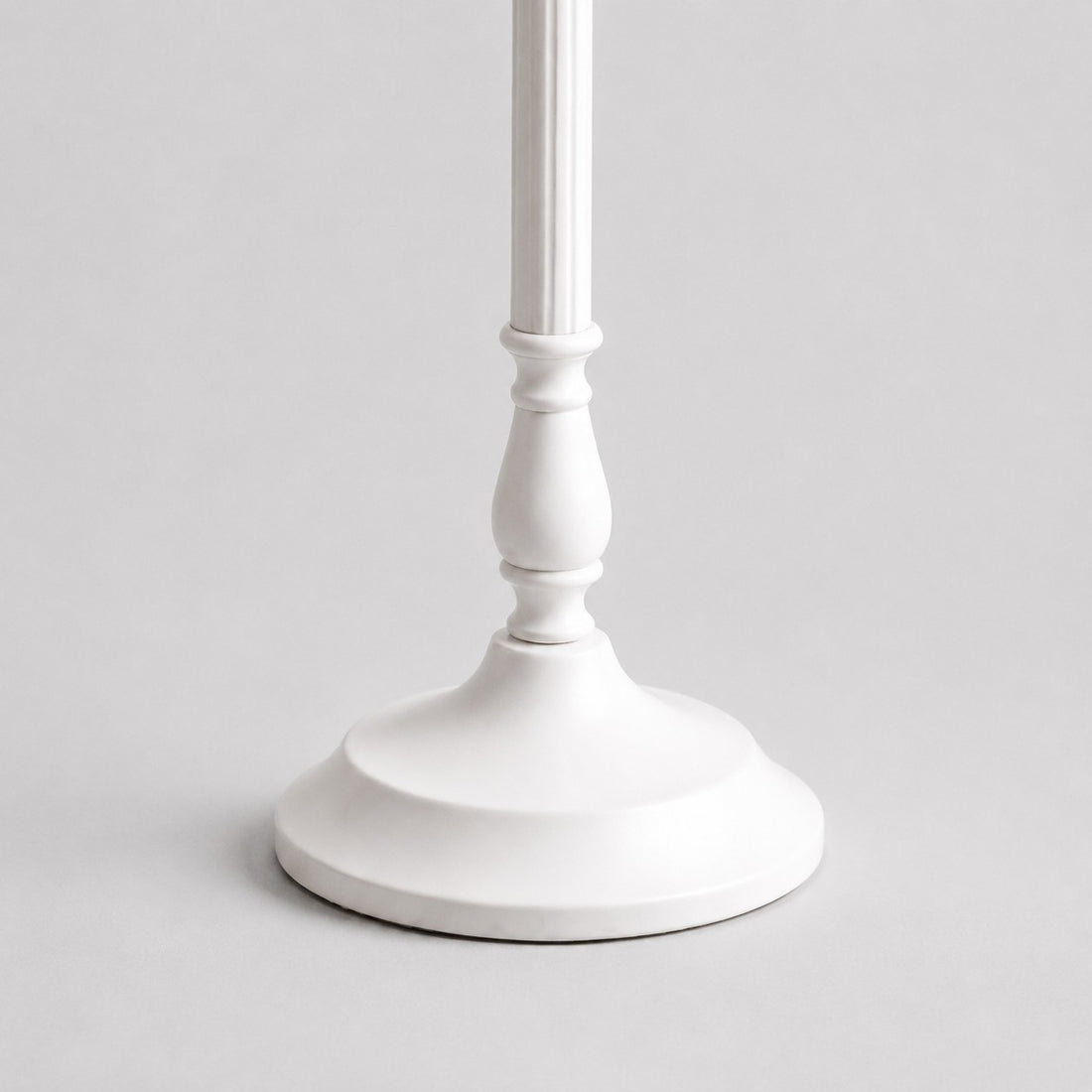 Close-up of sculpted white metal stem and smooth round lamp base