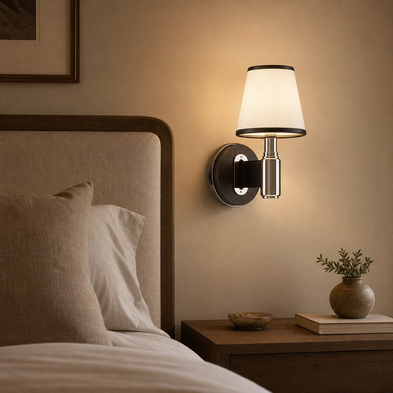 Black leather wall lamp glowing beside a bed