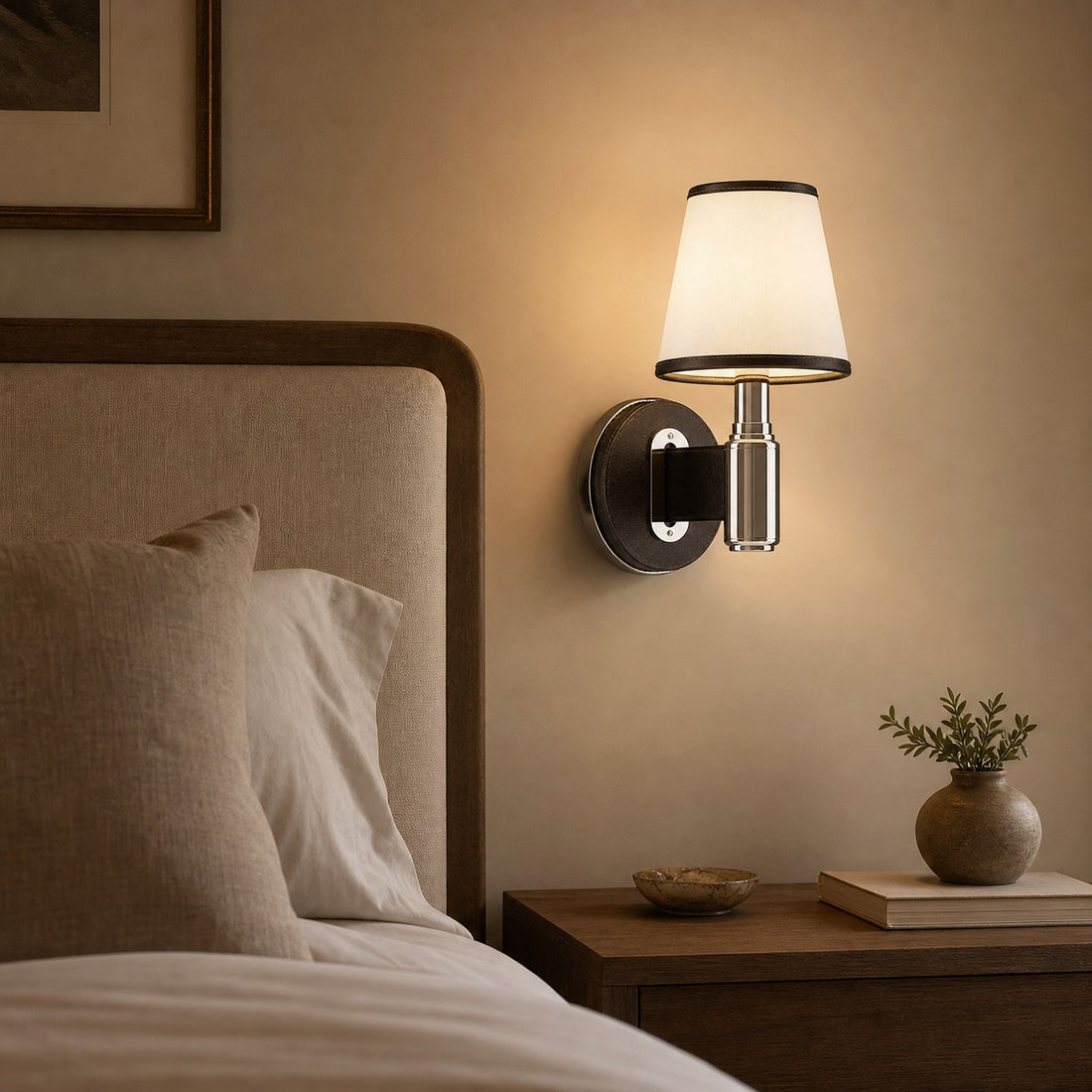 Black leather wall lamp glowing beside a bed