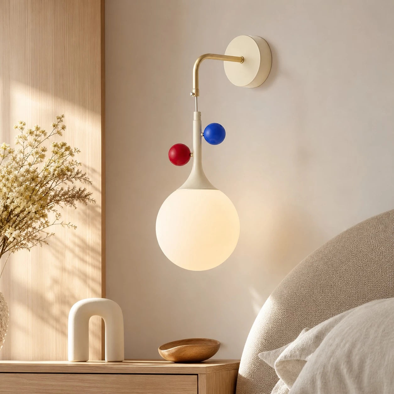 Cream orbit-disc globe wall sconce in a warm bedroom