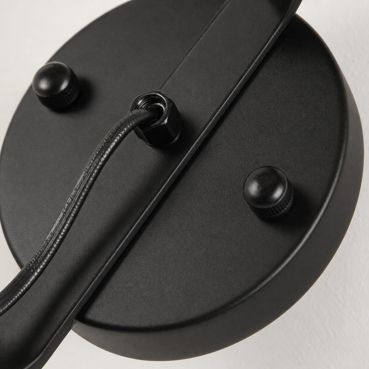 Close view of matte black round wall plate and cord detail