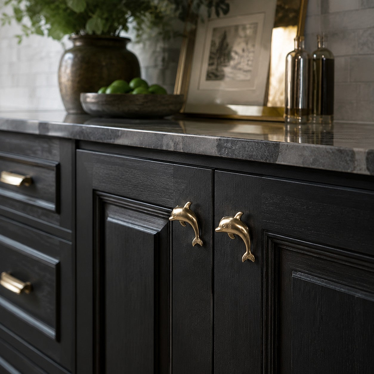 Natural brass dolphin handles on black cabinets with marble countertop