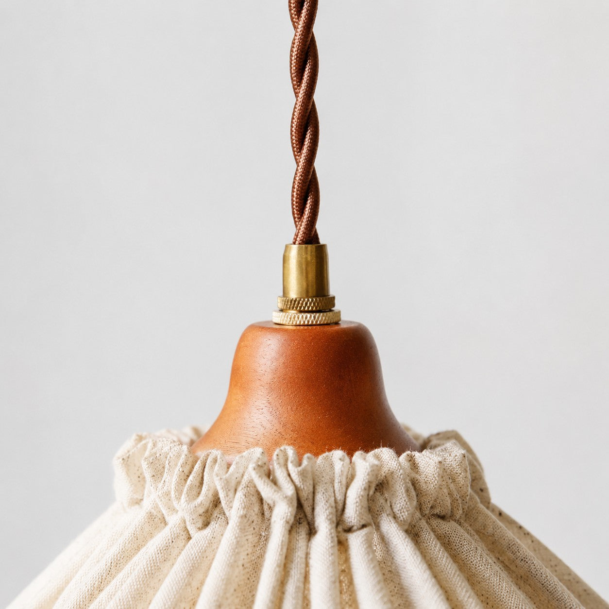 Close-up of twisted brown cord, brass fitting and warm wood socket cover