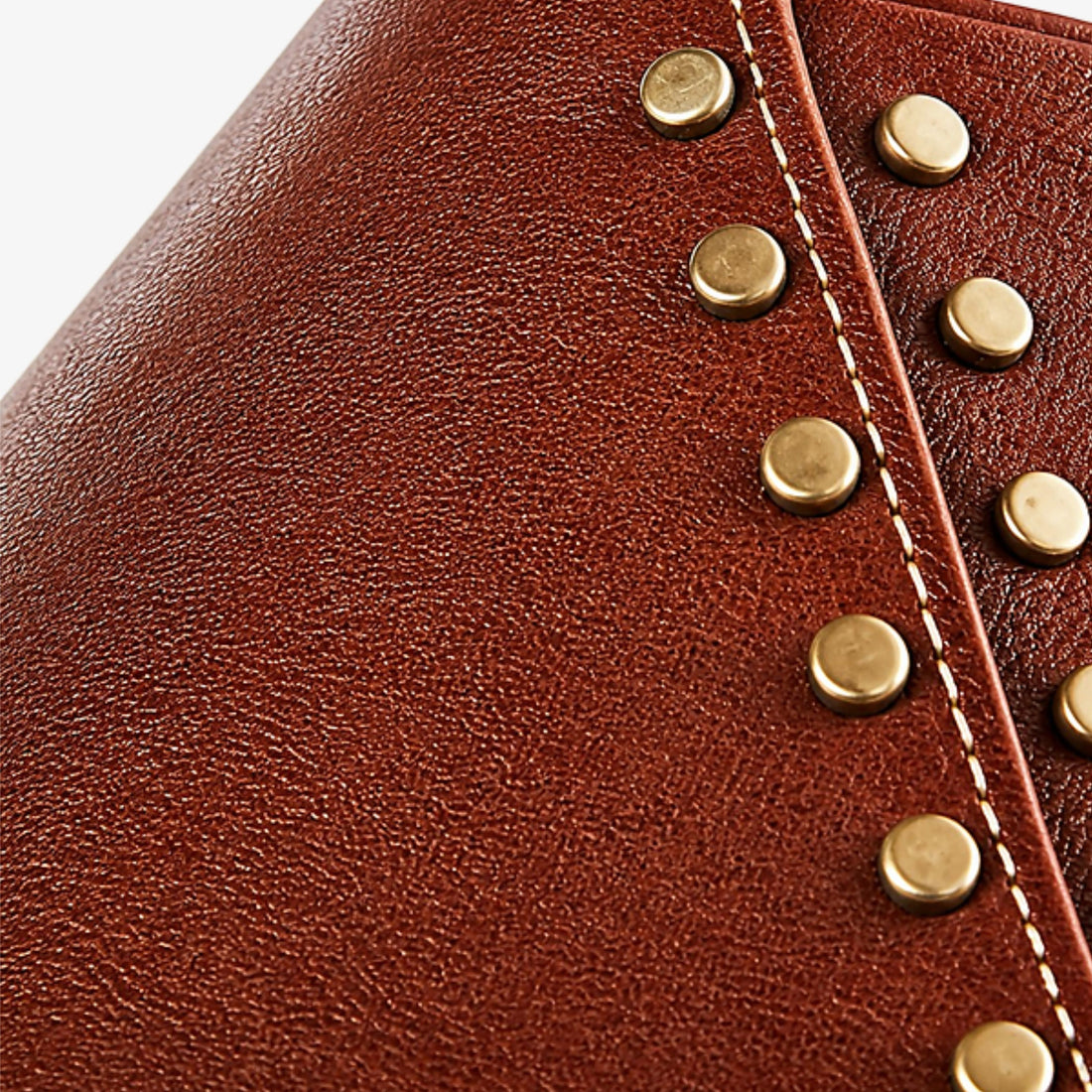 Hand-finished leather seam with antique brass rivets