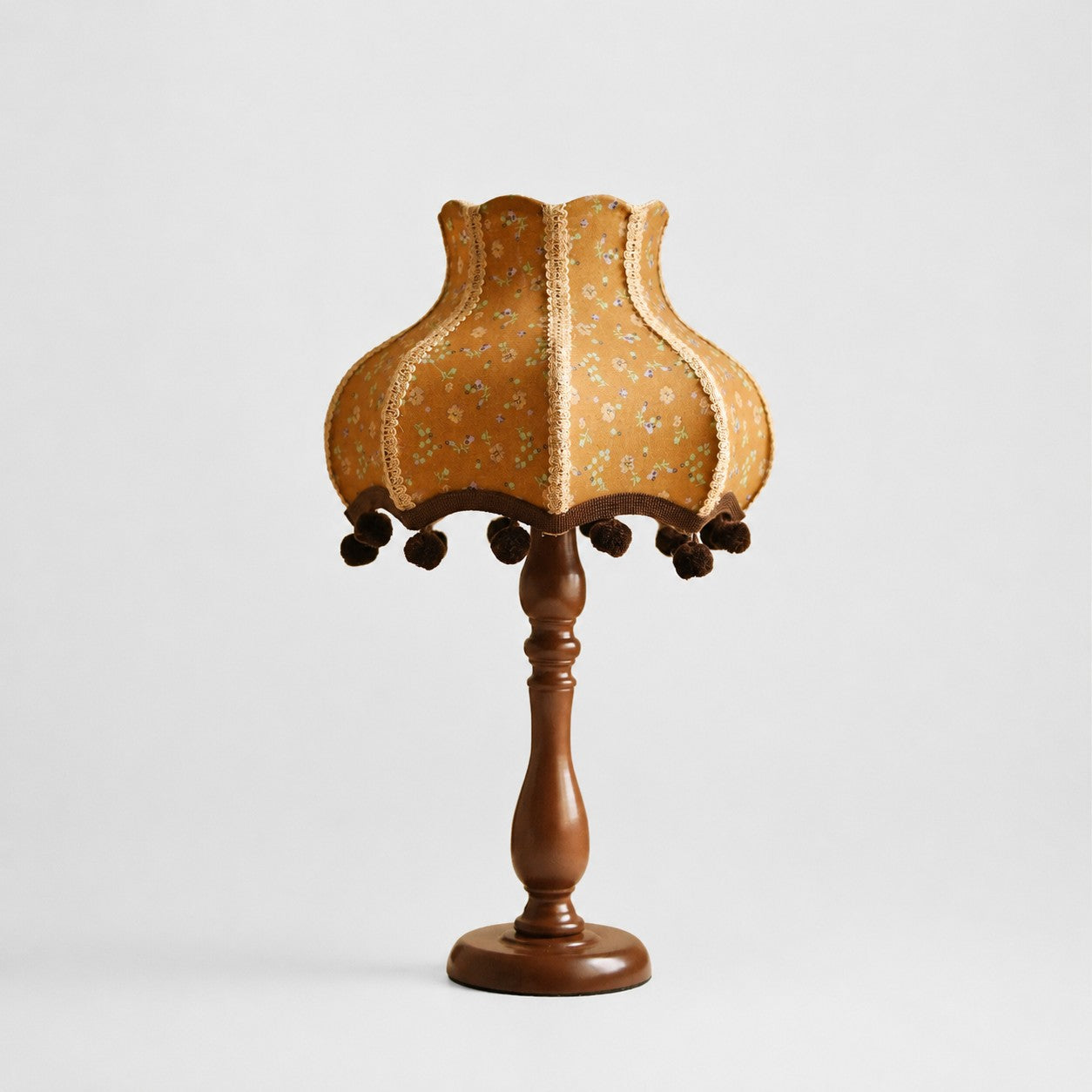 Vintage floral fabric table lamp with turned brown base on white background