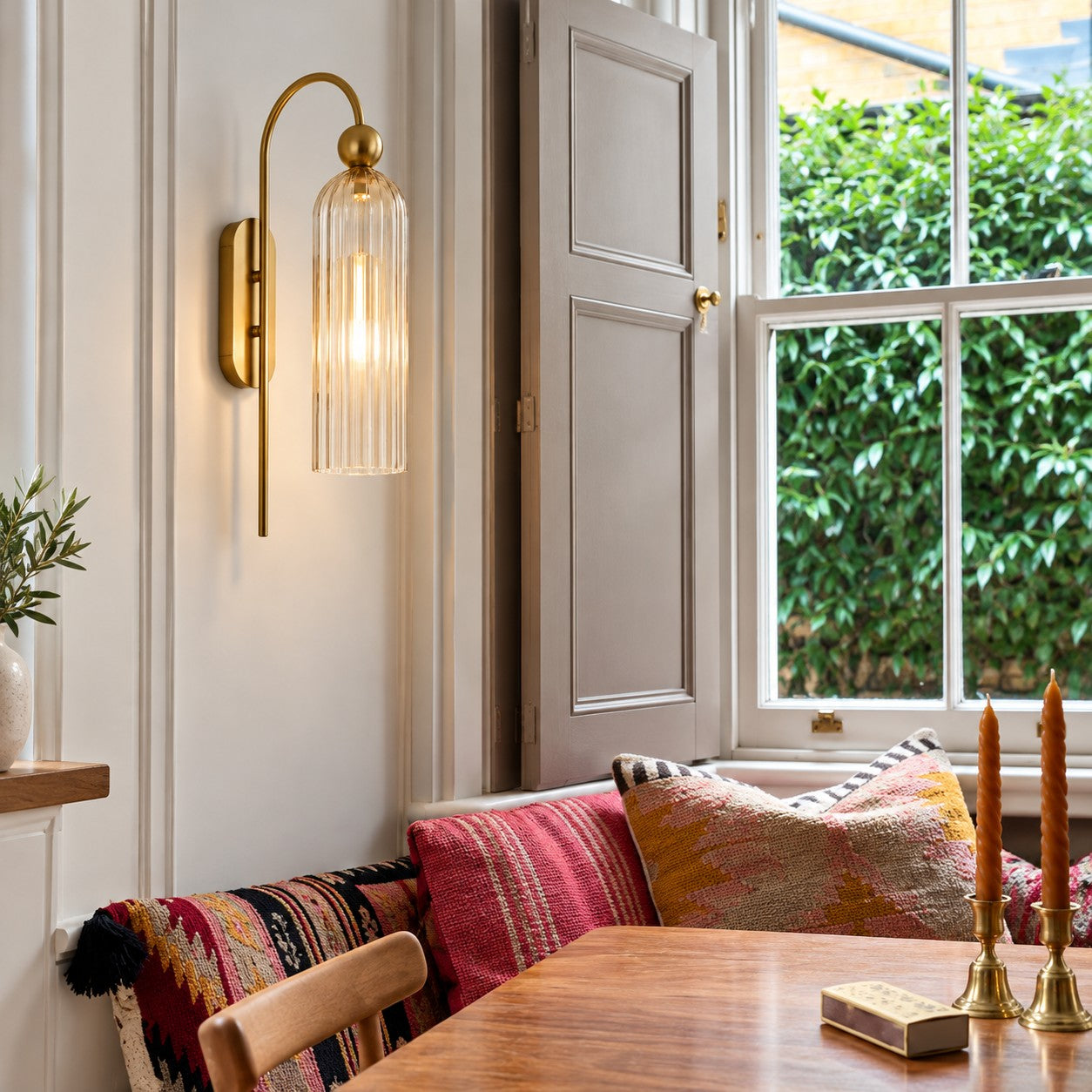 Aura clear glass wall sconce lit in a dining nook