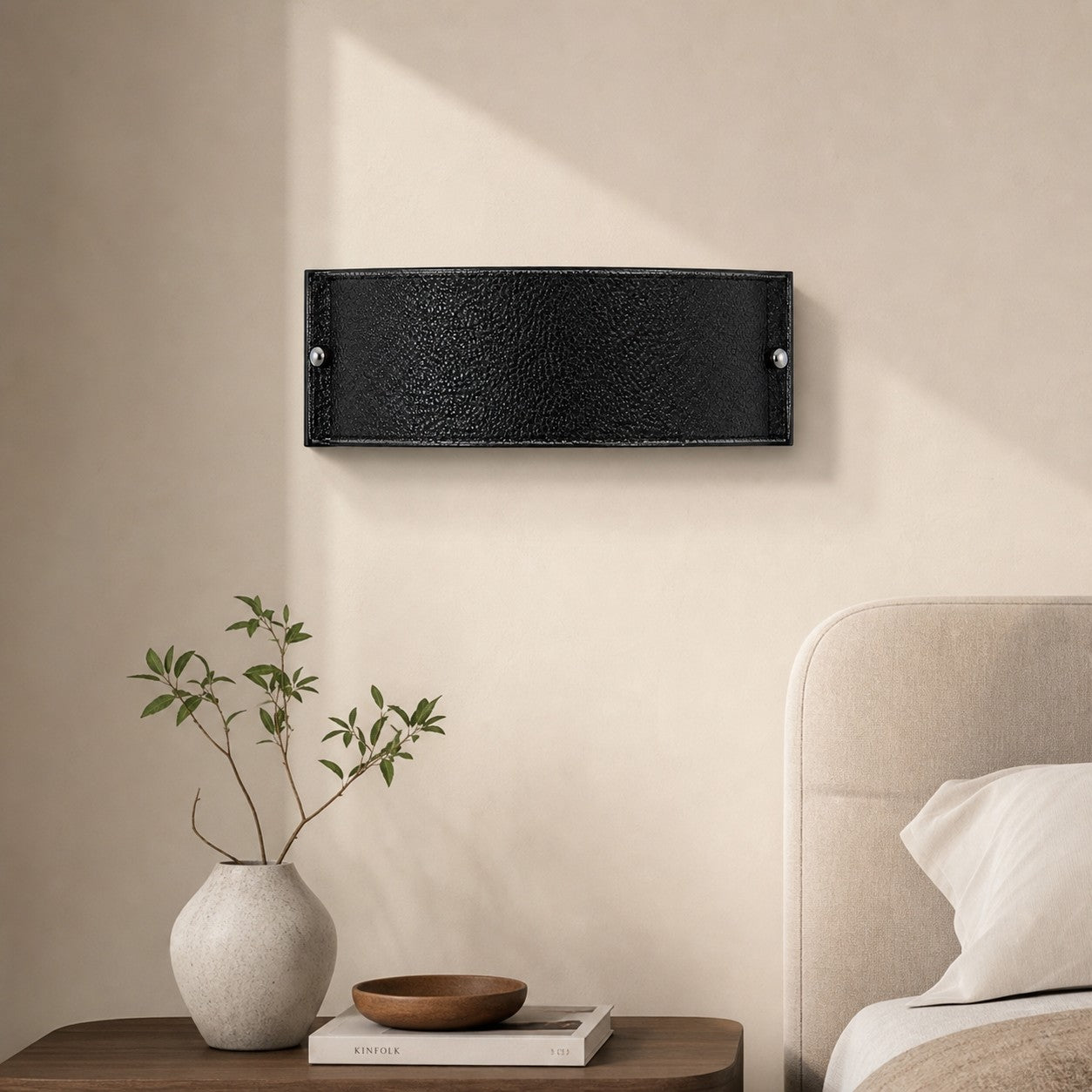 Black leather wall lamp beside a bed