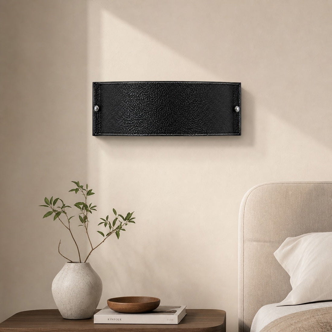 Black leather wall lamp beside a bed