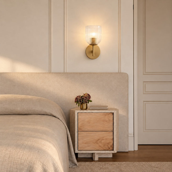 Ribbed glass sconce styled beside a paneled wall and stone nightstand