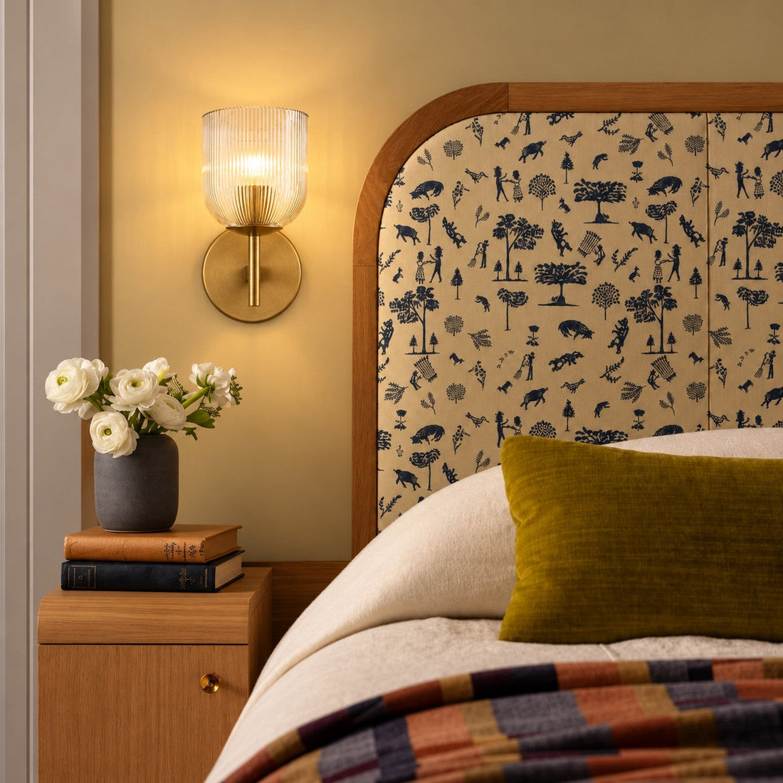Ribbed glass sconce styled beside a patterned arched headboard