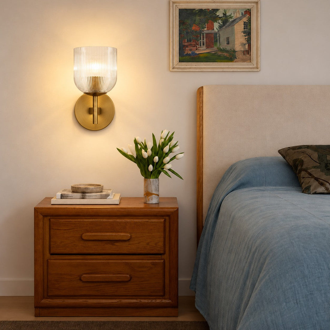 Ribbed glass sconce styled above a wood nightstand with tulips