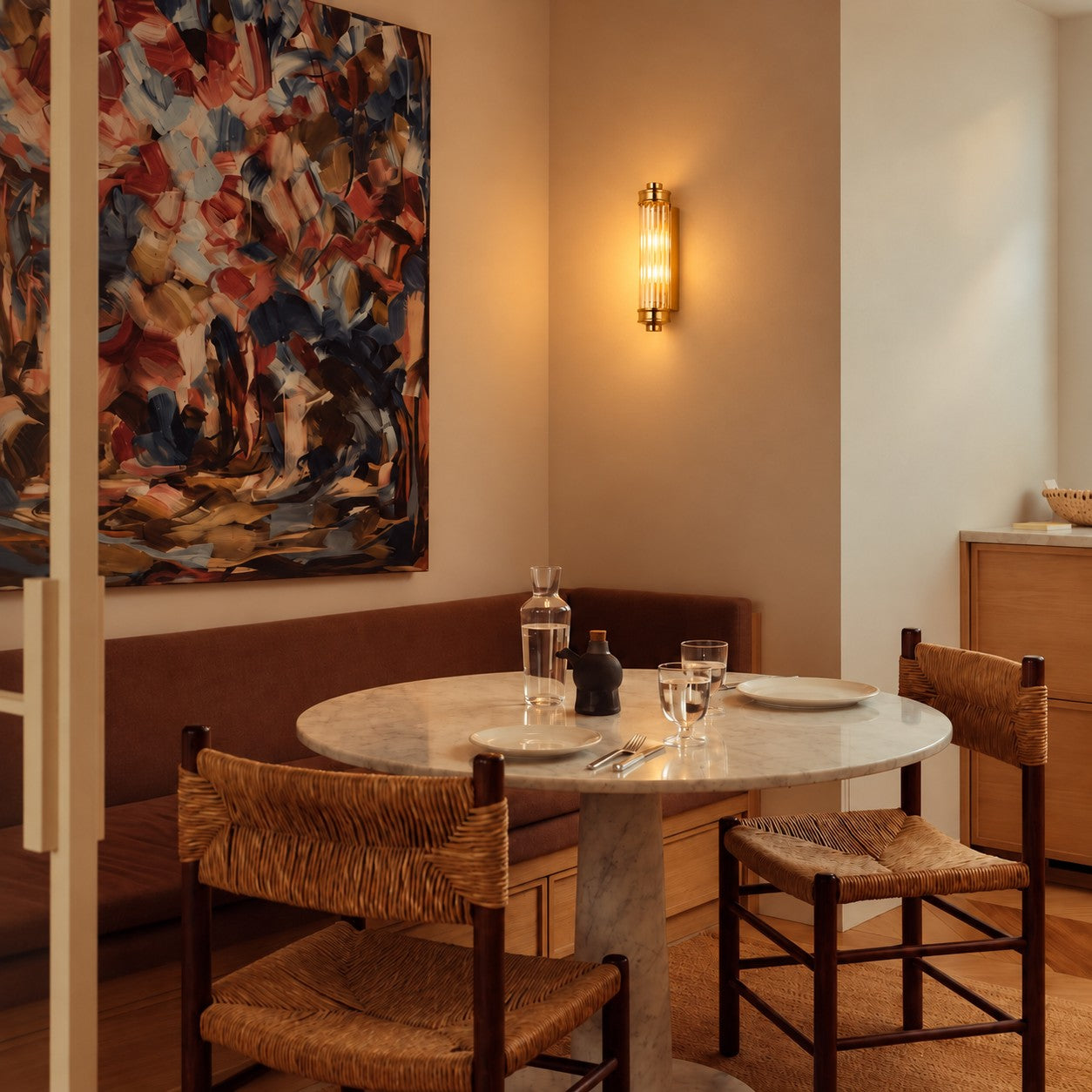Ribbed cylindrical wall sconce styled above a marble dining table
