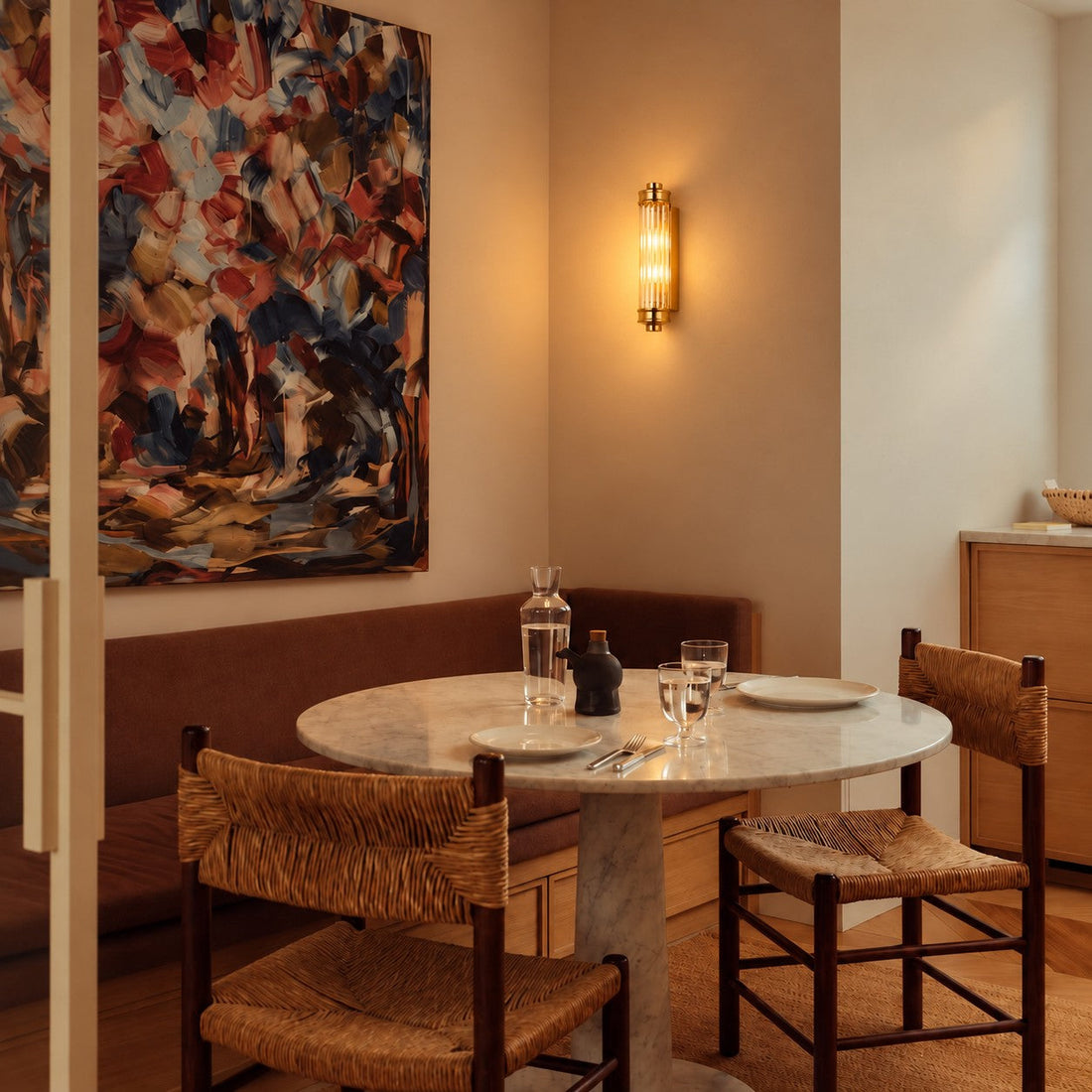Ribbed cylindrical wall sconce styled above a marble dining table