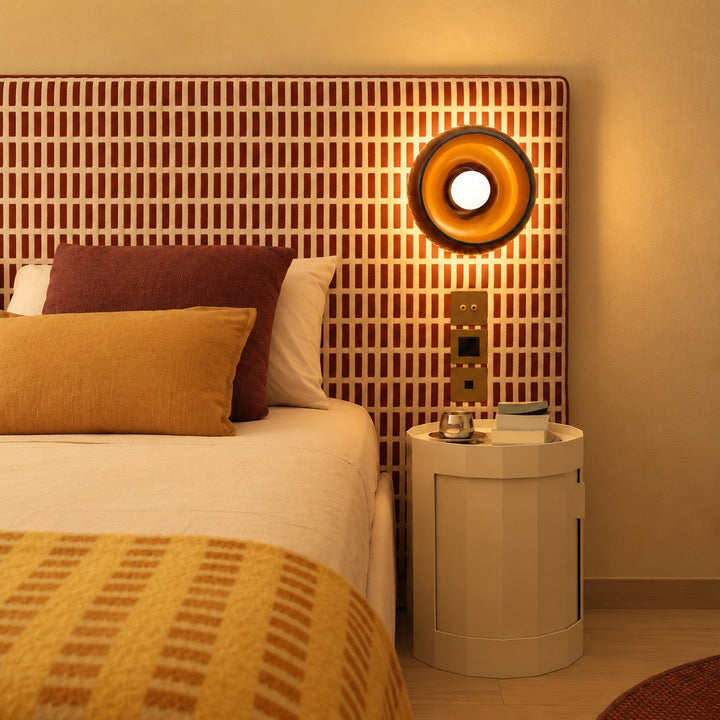 Amber bowl wall sconce styled beside a striped rust headboard