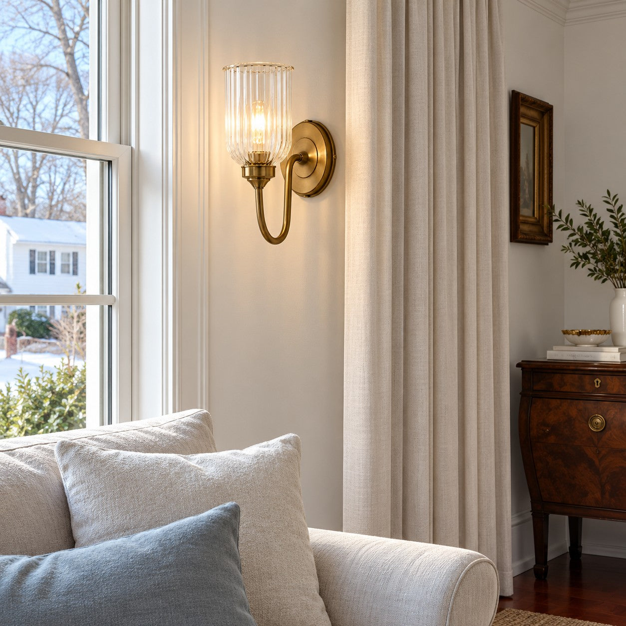 Vitrona ribbed glass wall sconce styled beside a living room window